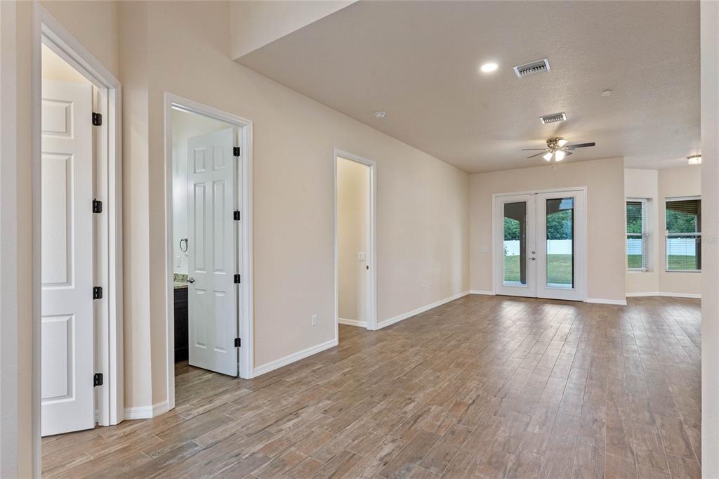 An interior view of a room with wood-look tile flooring, white doors, and glass doors — 1943 SIPES AVENUE, SANFORD, FL