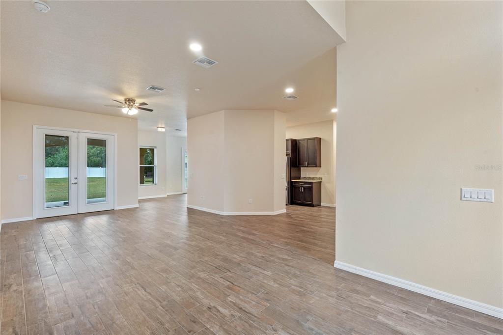 An open-concept living area features wood-look tile flooring, a ceiling fan, and a kitchen corner — 1943 SIPES AVENUE, SANFORD, FL