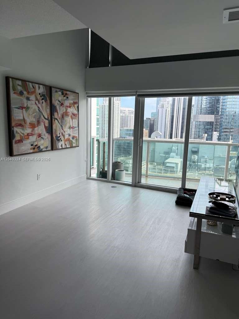 A modern living room features light wood flooring, abstract wall art, and floor-to-ceiling balcony windows — 41 SE 5th St # 1708, Miami FL 33131, MIAMI, FL