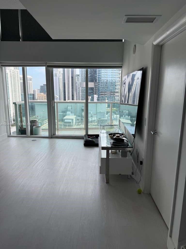 A modern living room features light flooring, a glass console table, and a balcony view — 41 SE 5th St # 1708, Miami FL 33131, MIAMI, FL