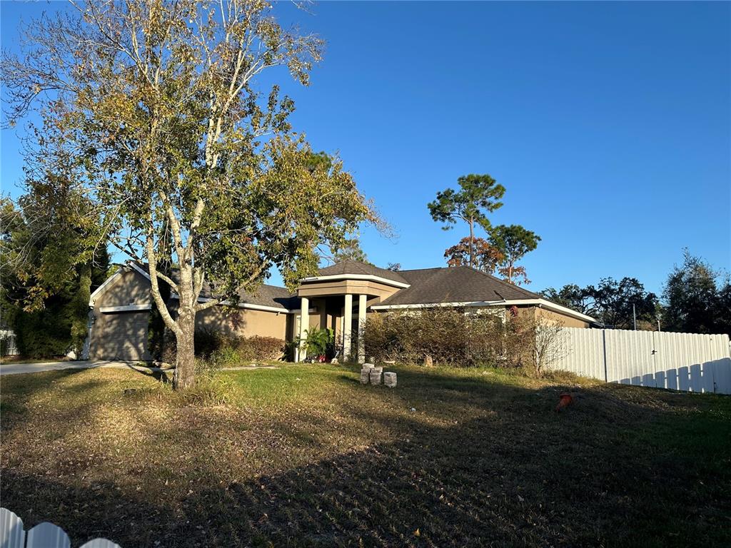 A single-story house with a tan exterior, a garage, and a white fence — 11382 MAHOPAC ROAD, WEEKI WACHEE, FL
