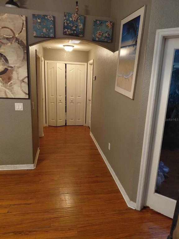 A hallway with wood-look flooring leads to a set of white bifold closet doors — 11382 MAHOPAC ROAD, WEEKI WACHEE, FL
