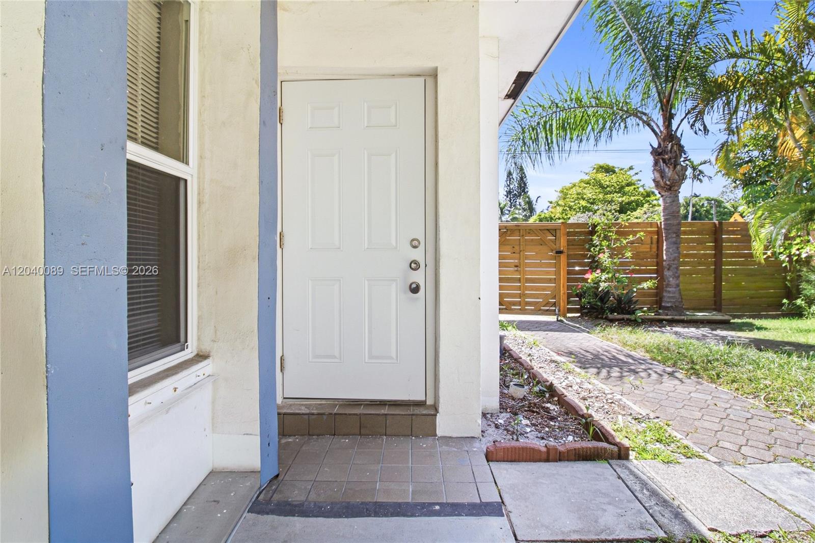 A white front door opens onto a tiled entryway next to a window and yard — 610 SW 2nd Ave # 1, Dania Beach FL 33004, DANIA BEACH, FL