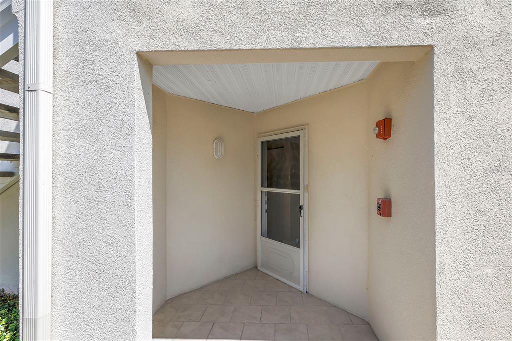 A recessed entryway features a white storm door, tiled floor, and two red fire alarms — 6011 BAHIA DEL MAR BOULEVARD UNIT 158, ST PETERSBURG, FL