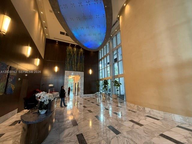 A modern building lobby features a marble floor, high ceilings, and a large blue light fixture — 185 SW 7th St # 3803, Miami FL 33130, MIAMI, FL