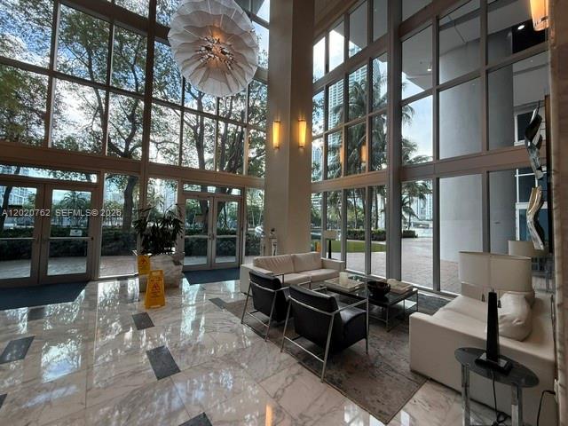 A modern building lobby features floor-to-ceiling windows, marble floors, and contemporary seating areas — 185 SW 7th St # 3803, Miami FL 33130, MIAMI, FL