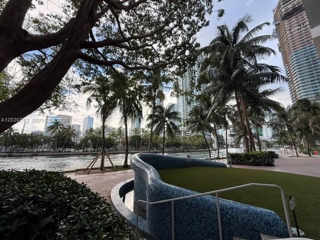 A curved blue-tiled wall borders a grassy area near a canal with palm trees — 185 SW 7th St # 3803, Miami FL 33130, MIAMI, FL