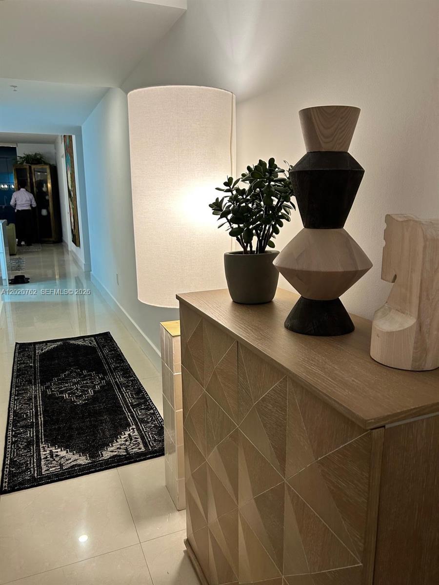 A hallway features a wooden cabinet topped with a decorative sculpture and a potted plant — 185 SW 7th St # 3803, Miami FL 33130, MIAMI, FL