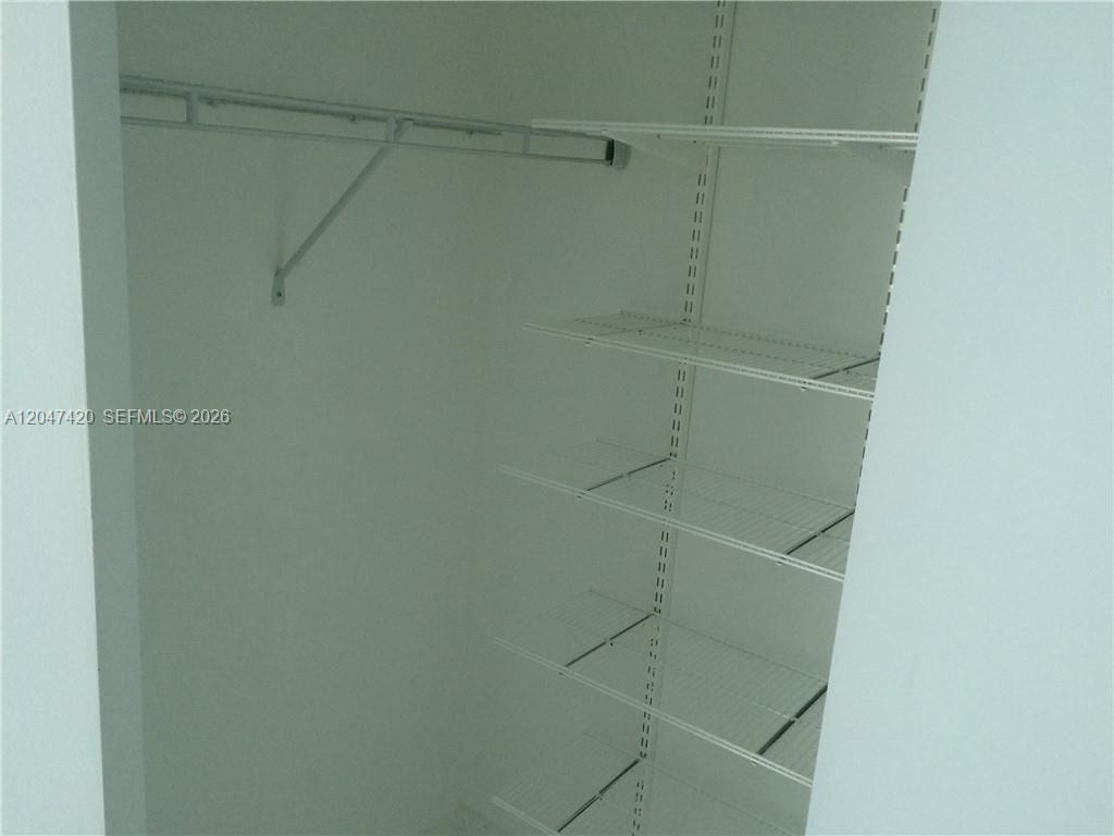 A walk-in closet features white wire shelving units and a hanging rod against plain walls — 55 SE 6th St # 2807, Miami FL 33131, MIAMI, FL