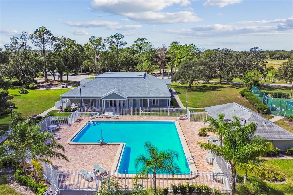 An aerial view of a community swimming pool and clubhouse surrounded by trees and landscaping — 12831 CASTLE OAKS DRIVE, HUDSON, FL