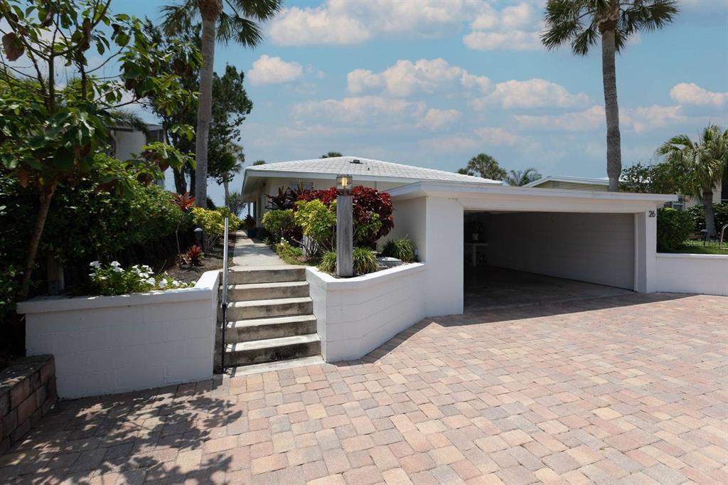 A paved driveway leads to a white house with a carport and concrete stairs — 6020 MIDNIGHT PASS ROAD UNIT 26, SARASOTA, FL