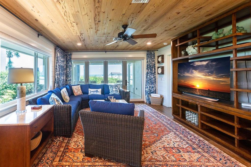 A living room features a blue sectional sofa, wood-paneled ceiling, and a large media console — 6020 MIDNIGHT PASS ROAD UNIT 26, SARASOTA, FL