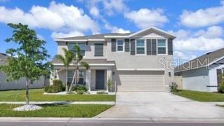 A two-story suburban house with a light-colored stucco exterior and a two-car garage — 16747 SUNBURST LAKE STREET, WIMAUMA, FL