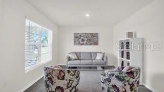 A living room features a gray sofa, two floral armchairs, and a white bookshelf — 16747 SUNBURST LAKE STREET, WIMAUMA, FL