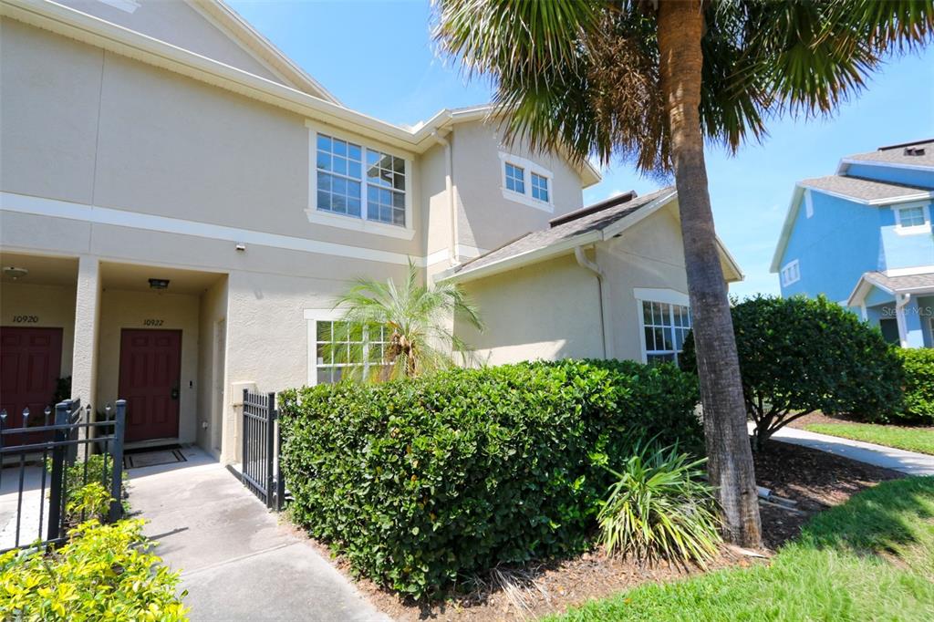 A two-story tan townhouse with a red door, a palm tree, and landscaping — 10922 WINTER CREST DRIVE, RIVERVIEW, FL
