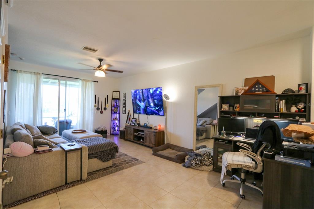 A living room with tile floors, a sectional sofa, a television, and a home office area — 10922 WINTER CREST DRIVE, RIVERVIEW, FL
