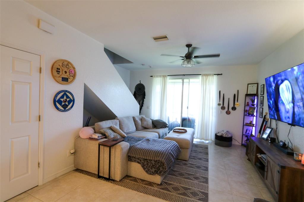 A living room features a gray sectional sofa, a television, and a staircase alcove — 10922 WINTER CREST DRIVE, RIVERVIEW, FL
