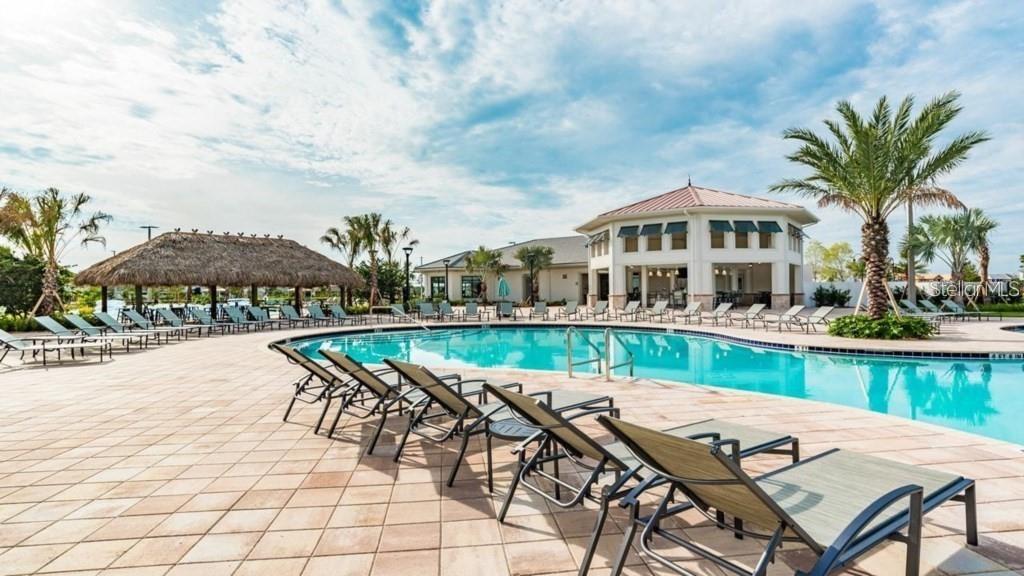 A swimming pool surrounded by lounge chairs, a thatched-roof pavilion, and a clubhouse building — 4830 MEMORIES LANE, KISSIMMEE, FL