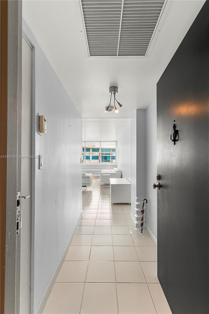A tiled hallway leads from a dark front door toward a bright, furnished living area — 1420 Brickell Bay Dr # 1405C, Miami FL 33131, MIAMI, FL