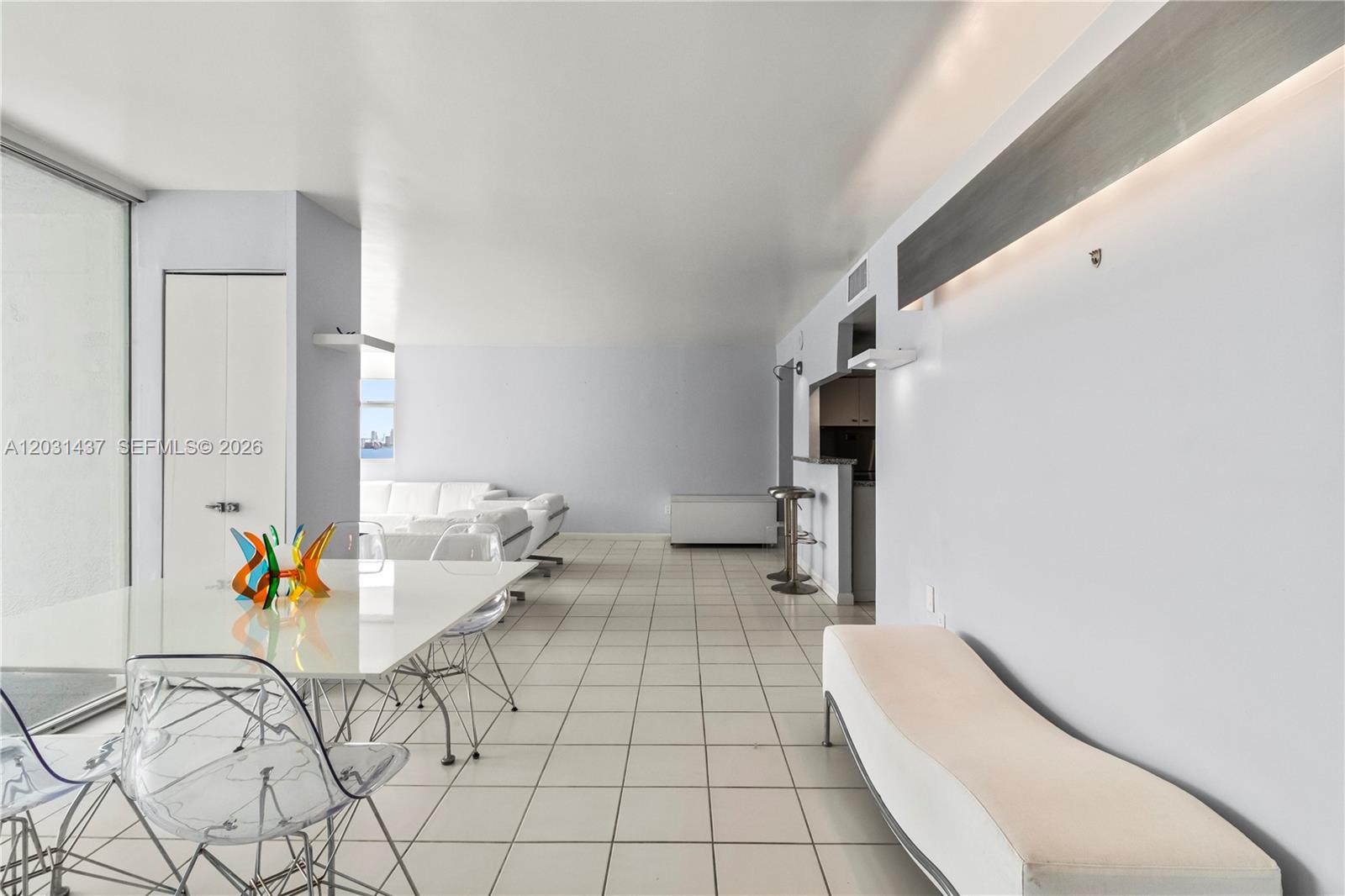 A bright, open-concept living and dining area features white tile flooring and modern furniture — 1420 Brickell Bay Dr # 1405C, Miami FL 33131, MIAMI, FL