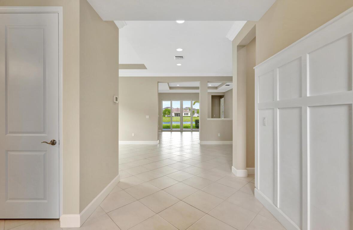 A bright entryway with tile floors leads to a living area with glass patio doors — 15684 Goldfinch Circle, FL 33470, FL