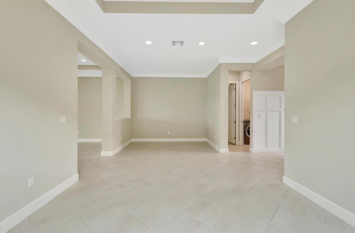An empty room with beige walls, recessed lighting, and light-colored diagonal floor tiles — 15684 Goldfinch Circle, FL 33470, FL