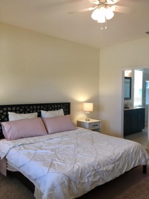 A bedroom features a bed with pink pillows, a bedside lamp, and a doorway to a bathroom — 7903 PLEASANT PINE CIRCLE, WINTER PARK, FL