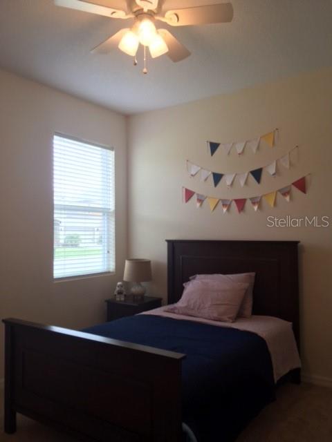A bedroom features a dark wood bed, a bedside lamp, and decorative bunting on the wall — 7903 PLEASANT PINE CIRCLE, WINTER PARK, FL
