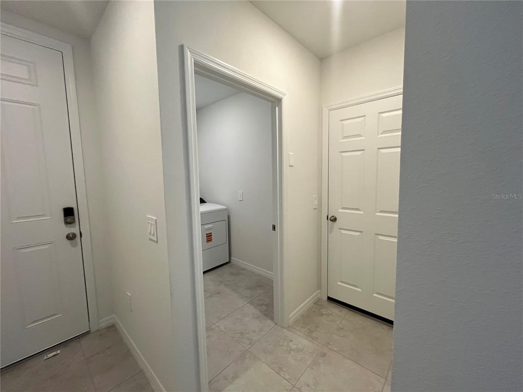 A hallway with tile flooring leads to a laundry room with a white washer and dryer — 3889 GIORGIO DRIVE, WINTER HAVEN, FL