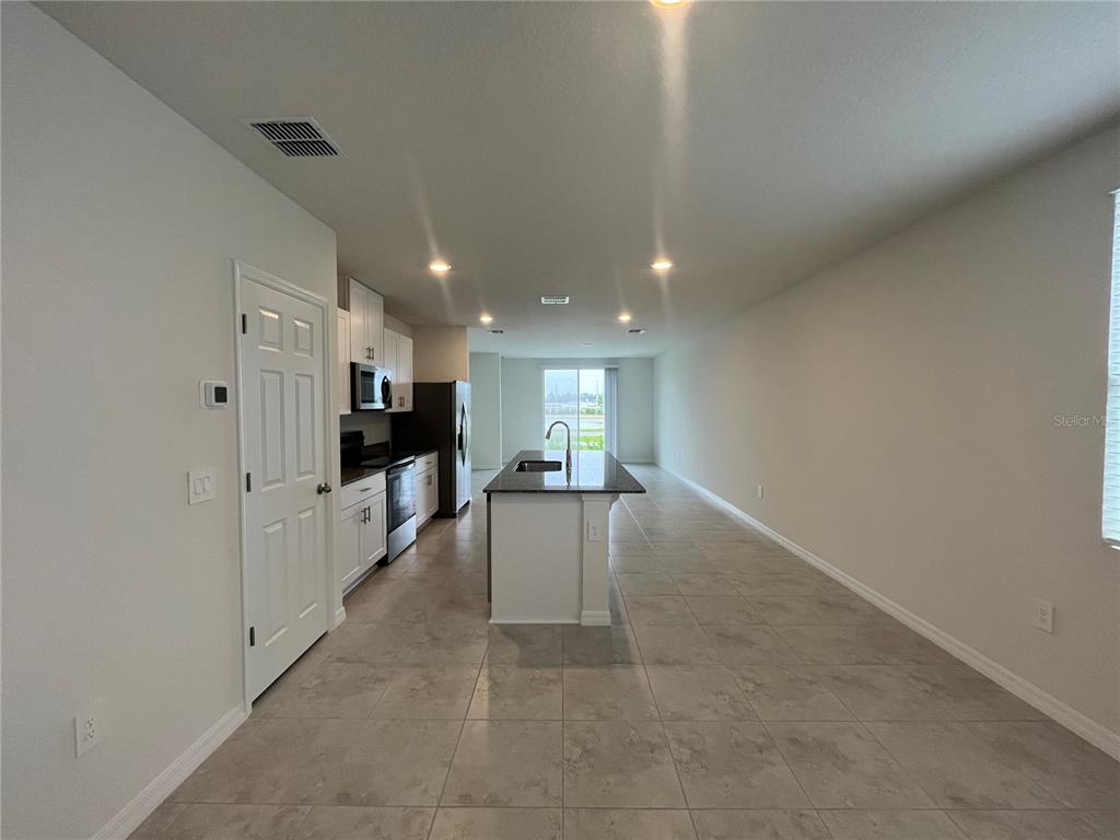 A kitchen with white cabinets, a dark island, and tile flooring in an open space — 3889 GIORGIO DRIVE, WINTER HAVEN, FL