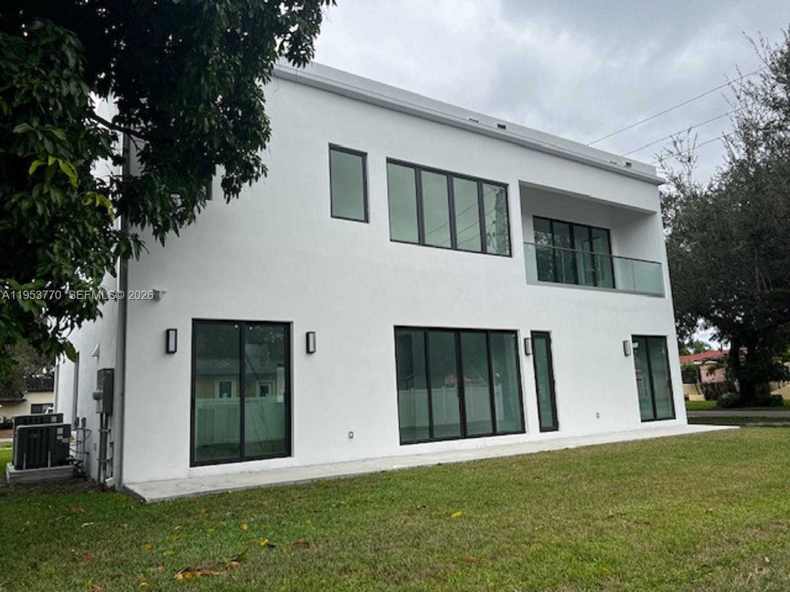 The exterior of a modern two-story white house features black-framed windows and a glass balcony — 2 Hough Dr, Miami Springs FL 33166, MIAMI SPRINGS, FL