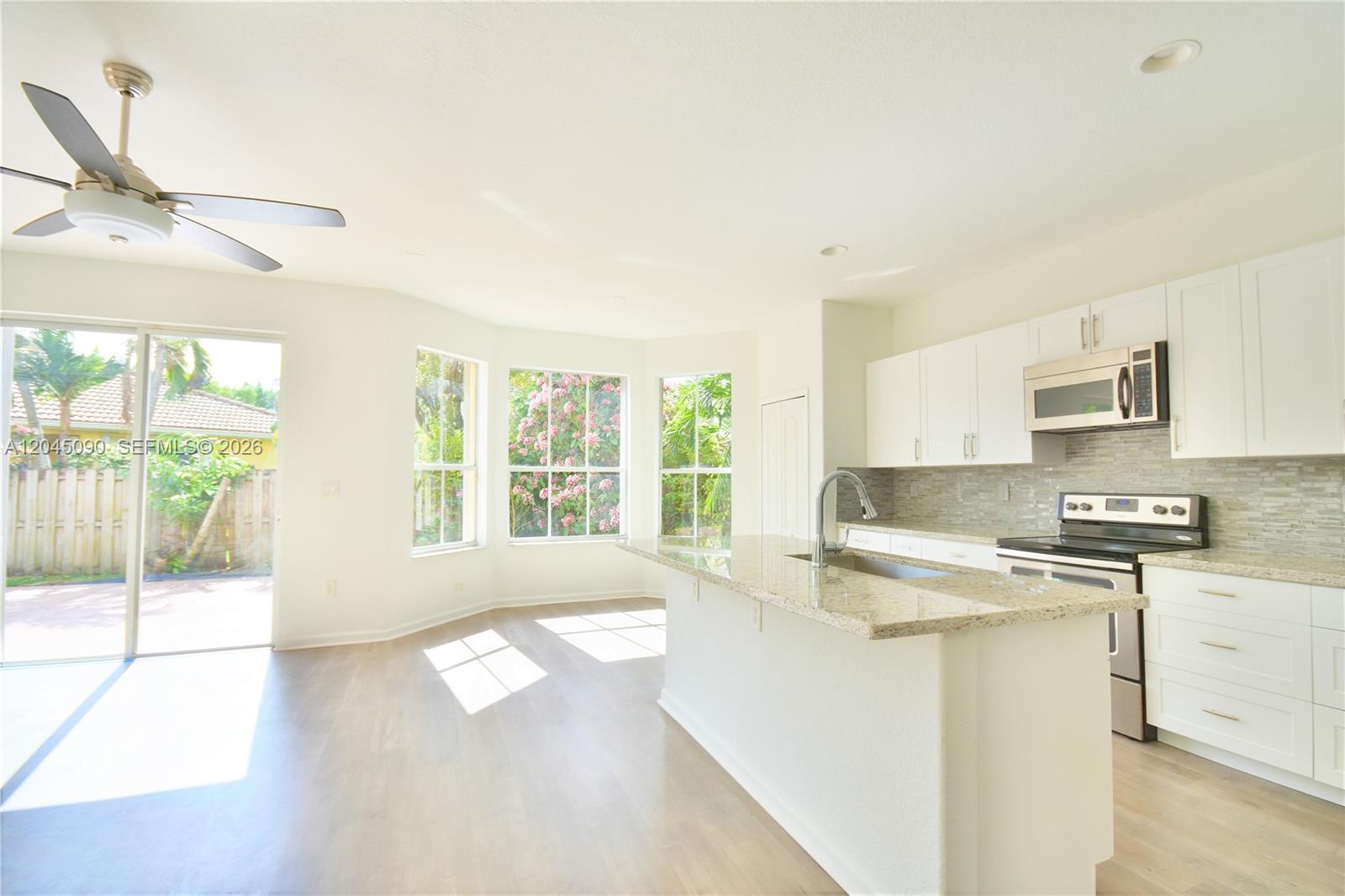 A bright kitchen features white cabinets, granite countertops, a center island, and large bay windows — 4534 NW 94th Pl, Doral FL 33178, DORAL, FL