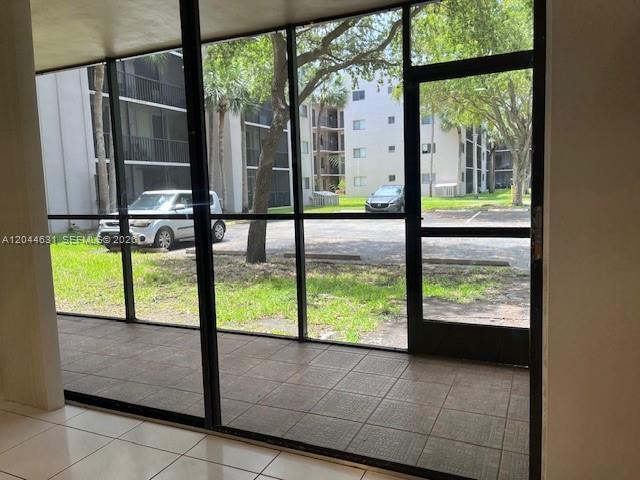 A screened-in patio with tiled flooring overlooks a parking lot and apartment buildings — 8540 SW 133rd Ave Rd # 123, Miami FL 33183, MIAMI, FL