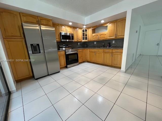 A kitchen features light wood cabinets, stainless steel appliances, and white tiled flooring — 8540 SW 133rd Ave Rd # 123, Miami FL 33183, MIAMI, FL