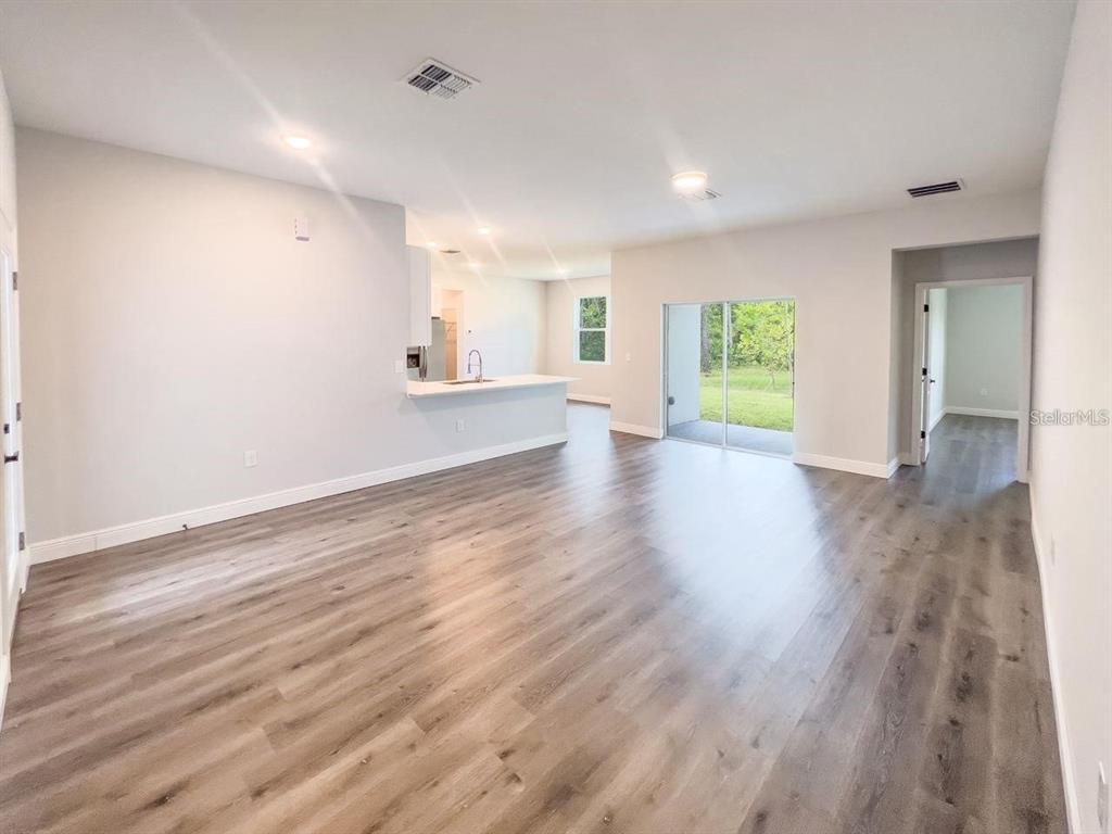 An open-concept living room features light gray walls, wood-look flooring, and a kitchen island — 1580 EAST PARKWAY, DELAND, FL