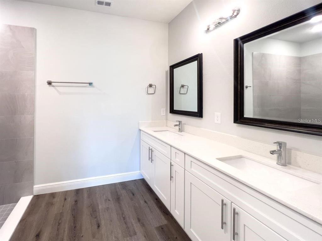 A bathroom features a double vanity with white cabinets, quartz countertops, and two framed mirrors — 1580 EAST PARKWAY, DELAND, FL