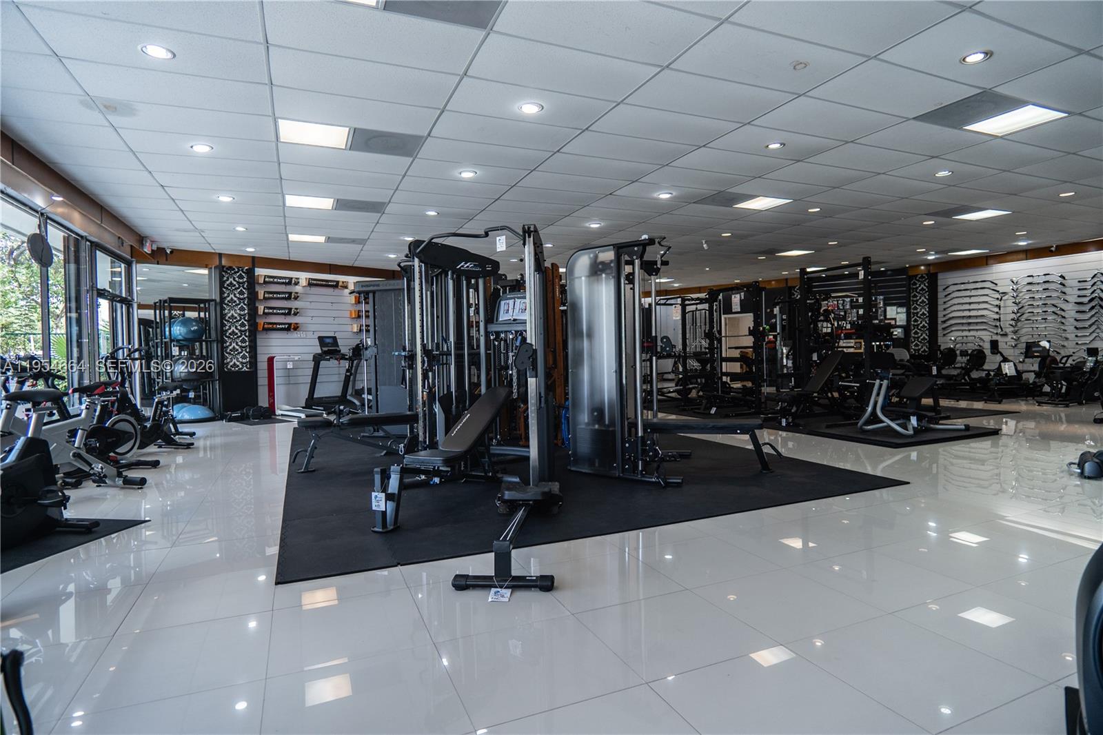A commercial gym showroom features various exercise equipment on black mats over white tile floors — 12253 S Dixie Hwy, Pinecrest FL 33156, PINECREST, FL