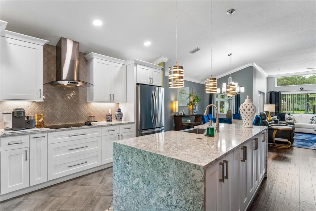 A modern kitchen features white cabinetry, a large granite island, and stainless steel appliances — 14439 MIDDLE FAIRWAY DRIVE, SPRING HILL, FL