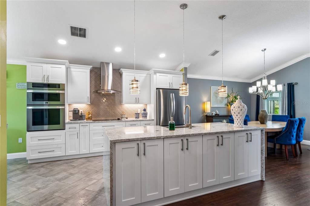 A kitchen with white cabinets, a granite-topped island, stainless steel appliances, and tile flooring — 14439 MIDDLE FAIRWAY DRIVE, SPRING HILL, FL