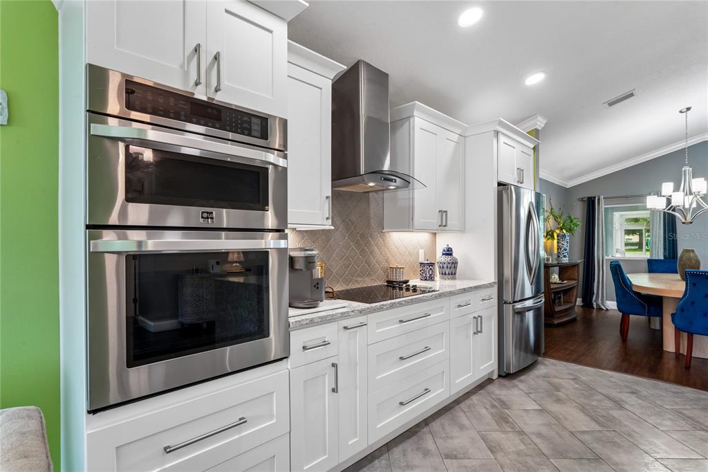 A modern kitchen features white cabinetry, stainless steel appliances, and a tiled backsplash — 14439 MIDDLE FAIRWAY DRIVE, SPRING HILL, FL