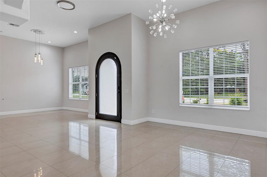 A bright, tiled room features a black arched front door and a modern sputnik chandelier — 7906 NAPOLEON STREET, ORLANDO, FL