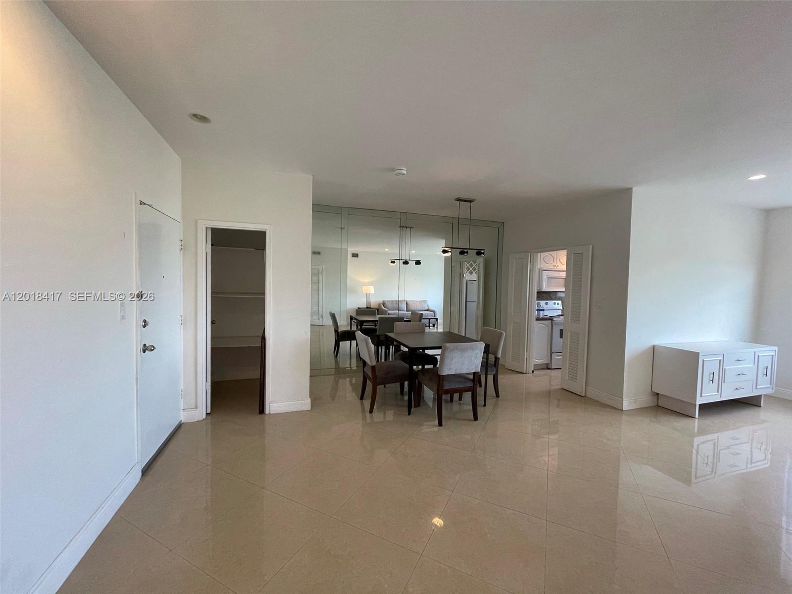 A dining area with a mirrored wall, tile flooring, and an adjacent kitchen — 4747 Collins Ave # 1102, Miami Beach FL 33140, MIAMI BEACH, FL