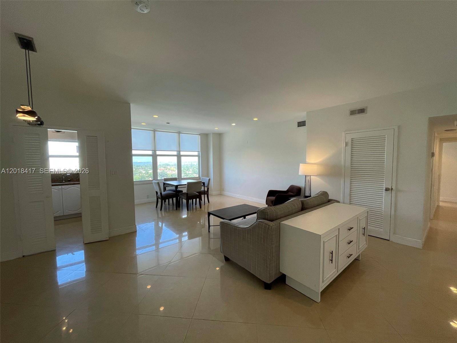 A living and dining area features light tile floors, white walls, and large windows — 4747 Collins Ave # 1102, Miami Beach FL 33140, MIAMI BEACH, FL