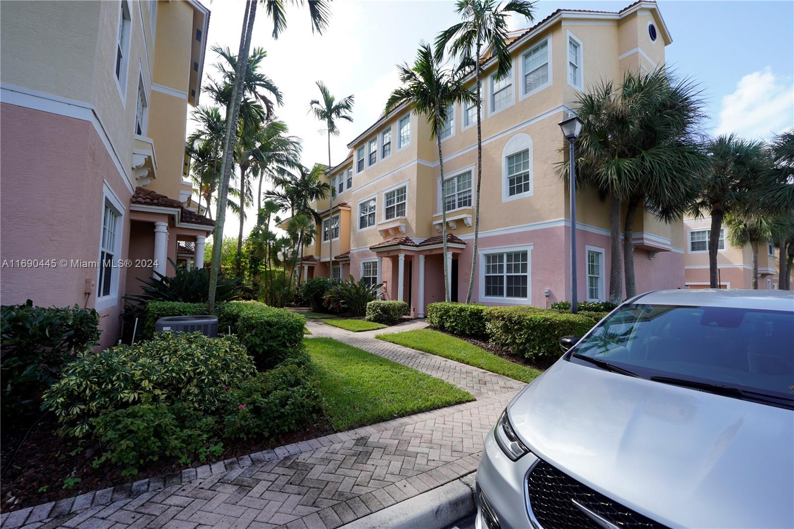 A multi-story residential building with pastel-colored stucco walls and palm trees in the foreground — 123 Harbors Way, Boynton Beach FL 33435, BOYNTON BEACH, FL
