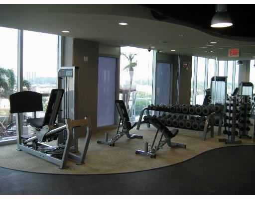 A fitness center features weight machines, a dumbbell rack, and large windows with outdoor views — 777 N ASHLEY DRIVE UNIT 1701, TAMPA, FL
