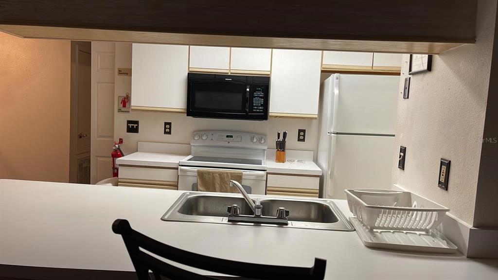 A kitchen features white cabinets, a microwave, a white stove, and a double-basin sink — 2456 SWEETWATER CLUB CIRCLE UNIT 20, KISSIMMEE, FL