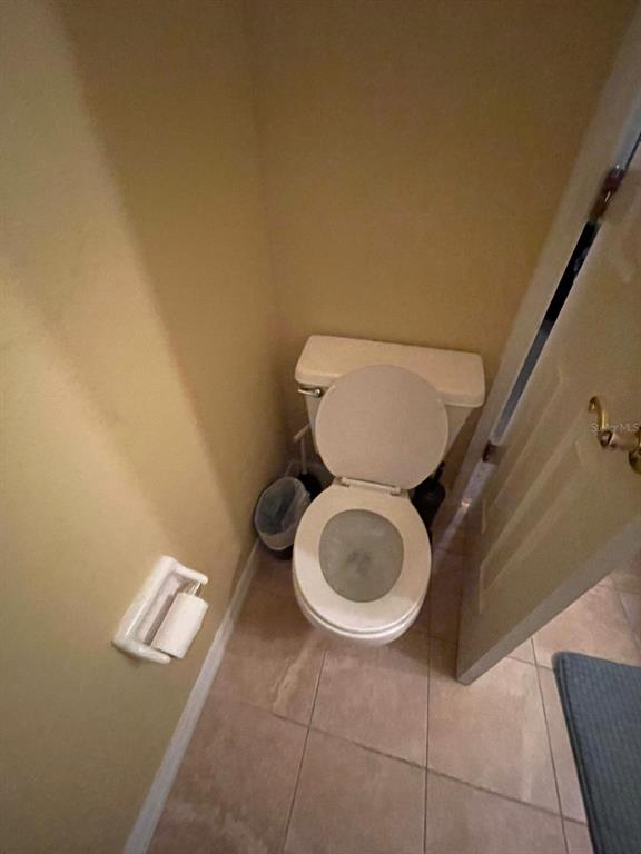 A small bathroom features a white toilet, a wall-mounted toilet paper holder, and tiled flooring — 2456 SWEETWATER CLUB CIRCLE UNIT 20, KISSIMMEE, FL