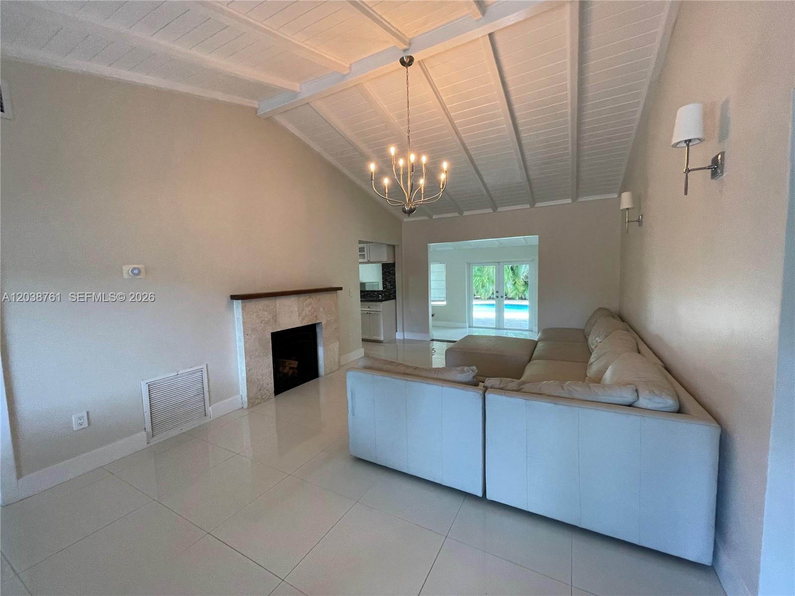 A living room features a fireplace, tiled floors, a vaulted ceiling, and a sectional sofa — 6129 SW 28th St, Miami FL 33155, MIAMI, FL