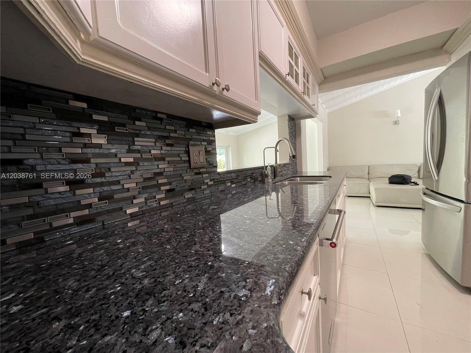 A kitchen features dark granite countertops, a mosaic tile backsplash, and white cabinets — 6129 SW 28th St, Miami FL 33155, MIAMI, FL