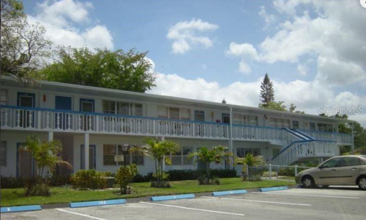 A two-story apartment building with white exterior walls, blue trim, and a second-floor balcony — 19 NEWPORT A, DEERFIELD BEACH, FL